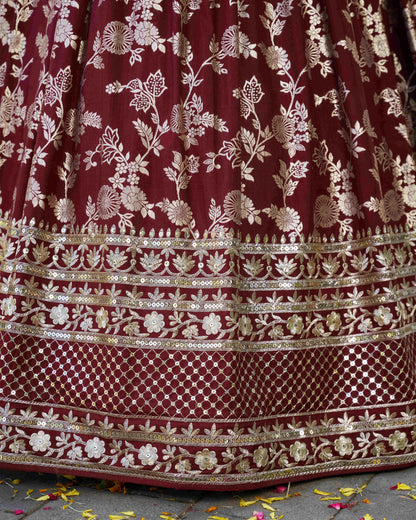 Maroon fabric with gold floral embroidery on a textured surface