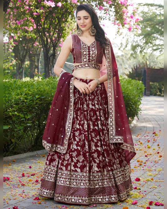 Woman in a maroon traditional outfit with floral patterns standing outdoors.