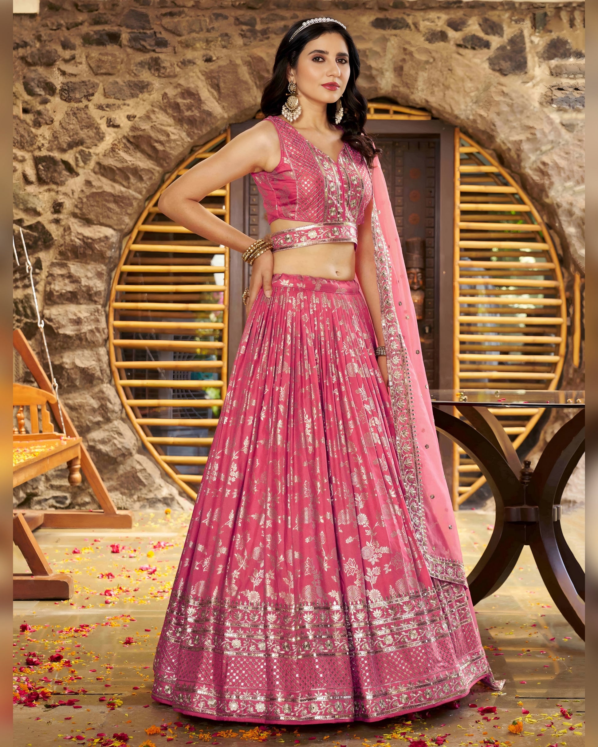 Woman in a pink traditional outfit standing against a stone wall.