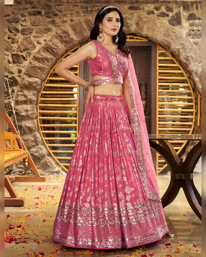 Woman in a pink traditional outfit standing against a stone wall.