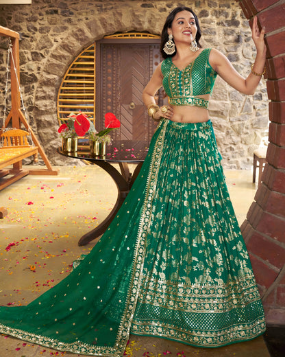 Woman in a green traditional outfit standing in a decorated room with flowers and a door.