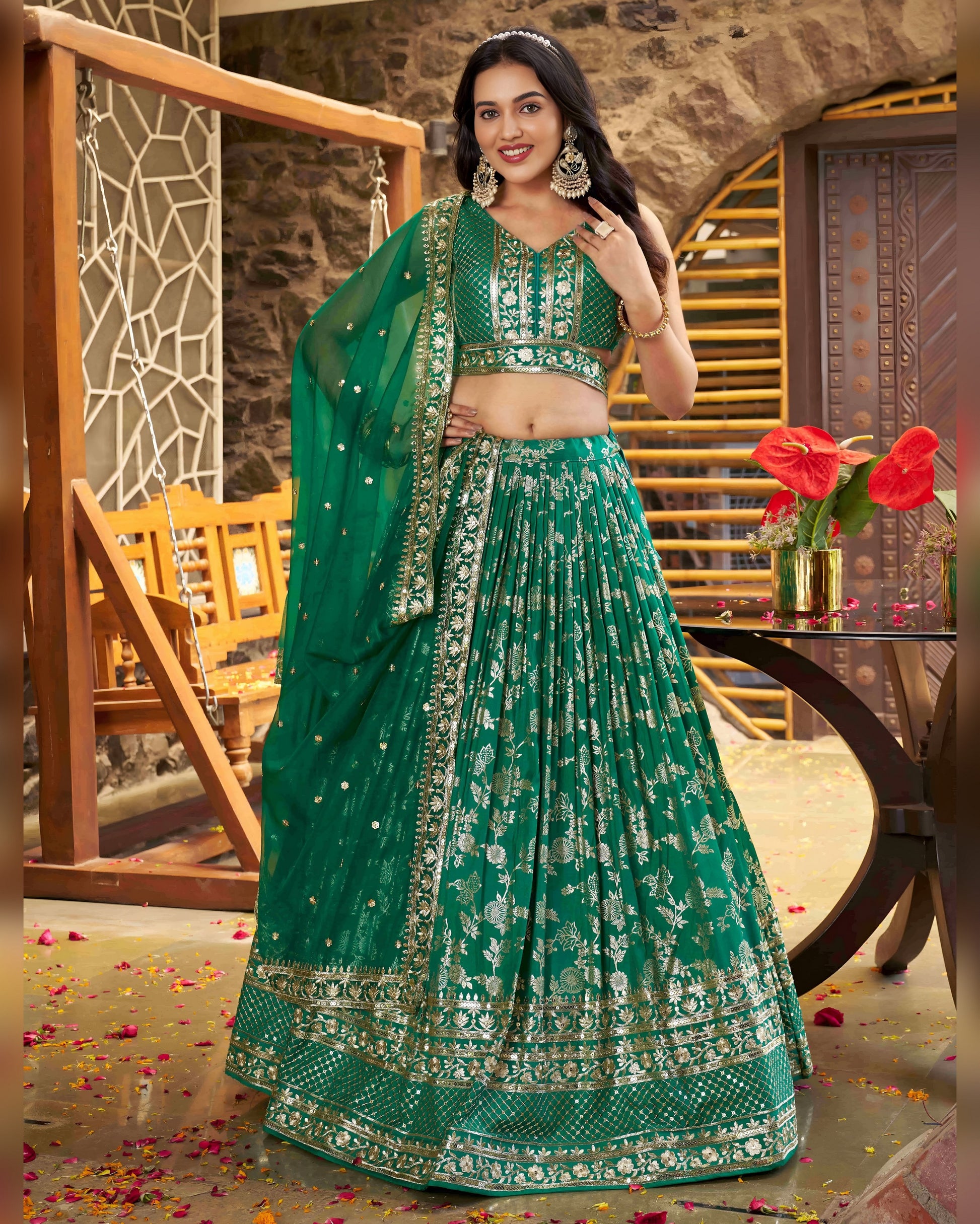Woman in a green traditional outfit with floral patterns in an indoor setting.