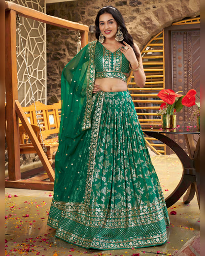 Woman in a green traditional outfit with floral patterns in an indoor setting.