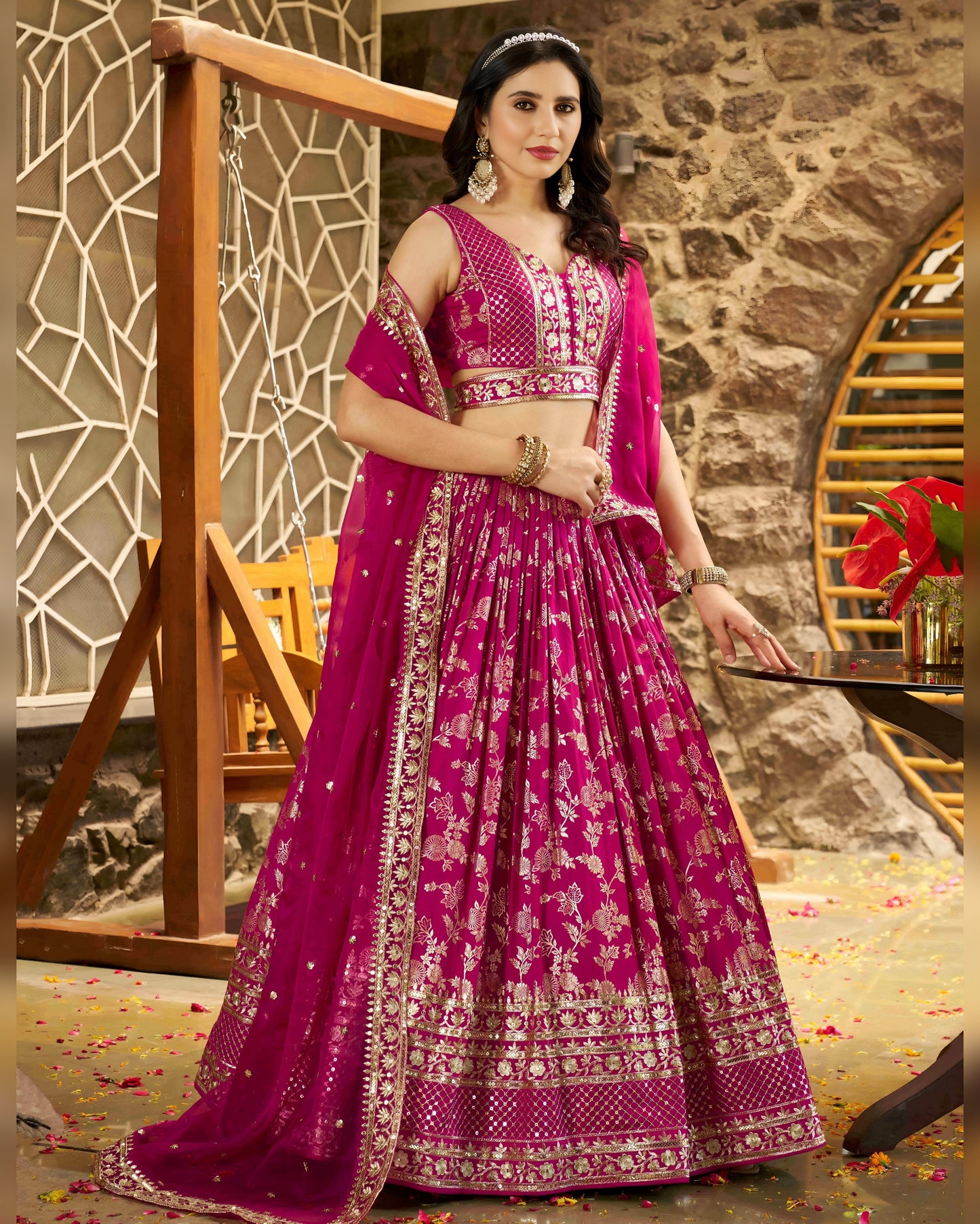 Woman in a pink traditional outfit with intricate designs in an indoor setting.