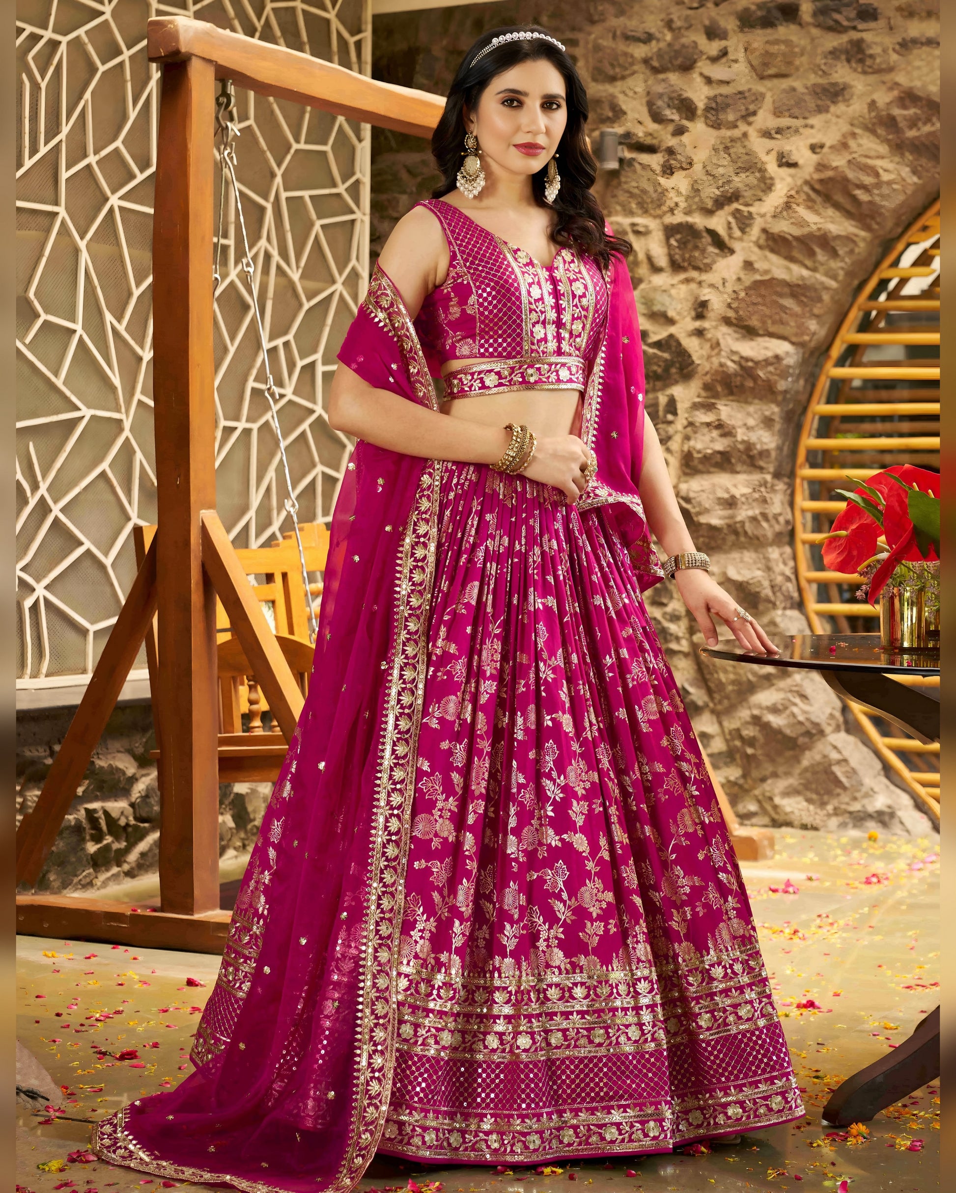 Woman in a pink traditional outfit with intricate designs in an indoor setting.