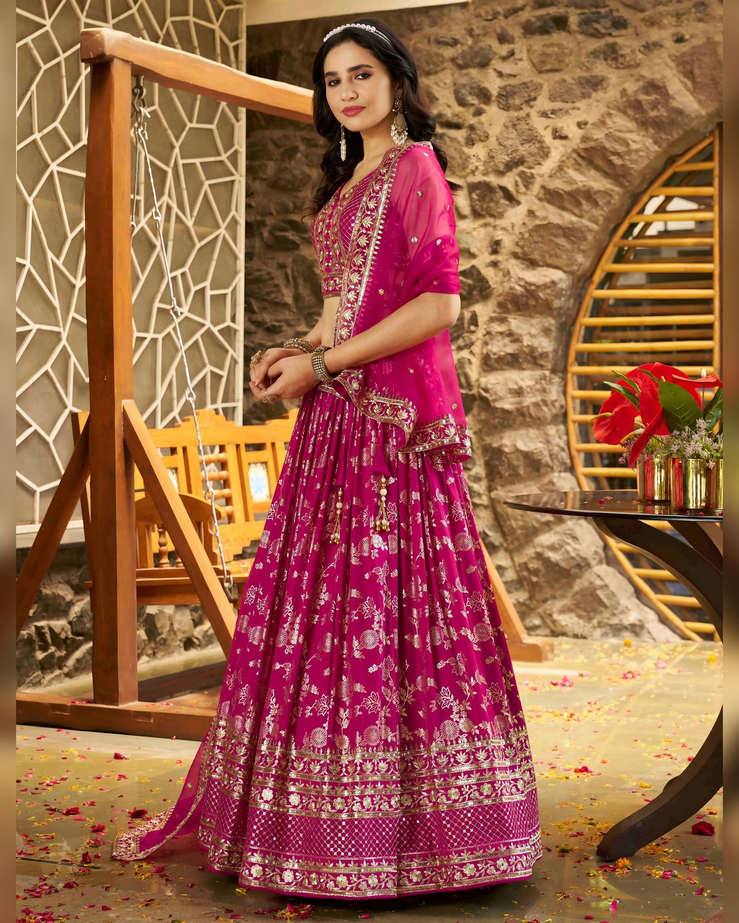 Woman in a pink traditional outfit standing in a decorative indoor setting.