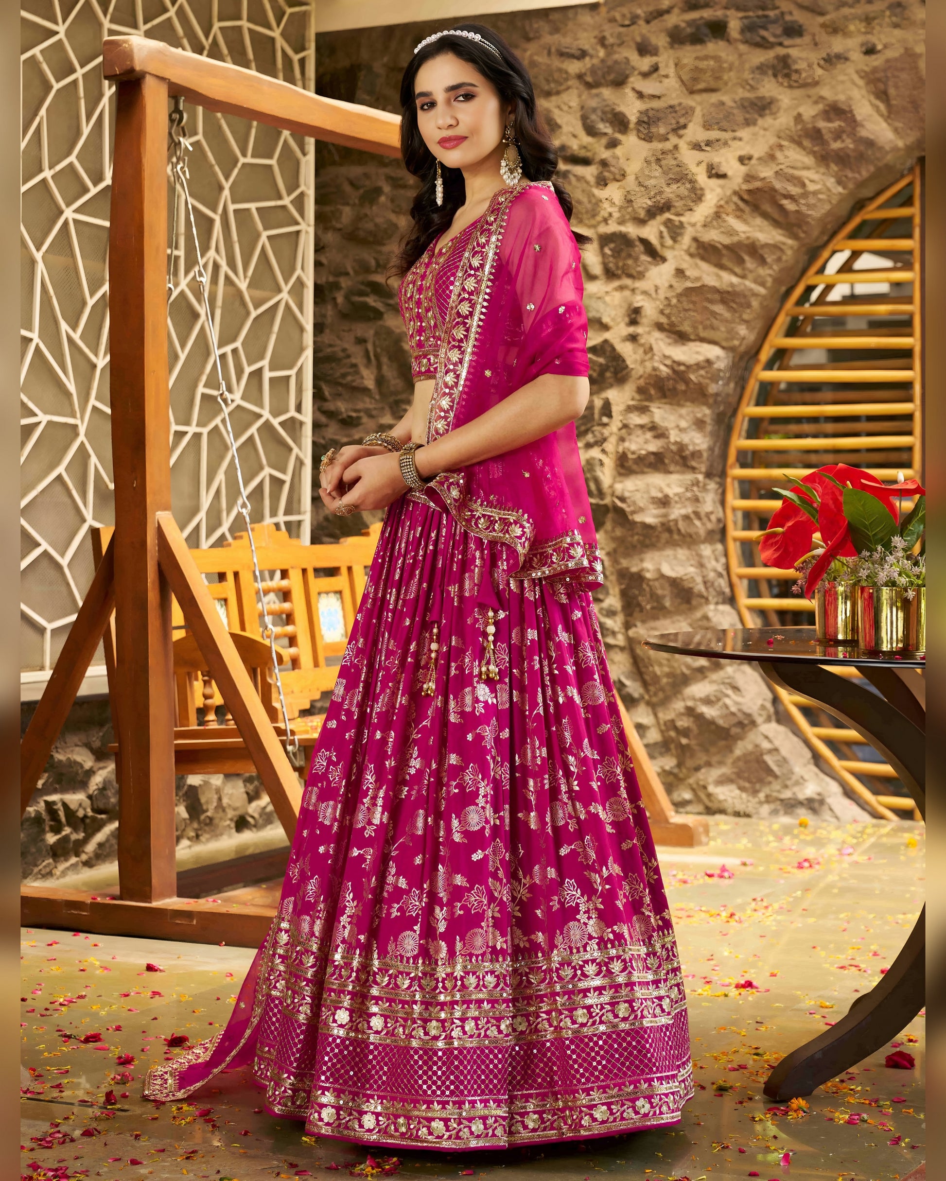 Woman in a pink traditional outfit standing in a decorative indoor setting.