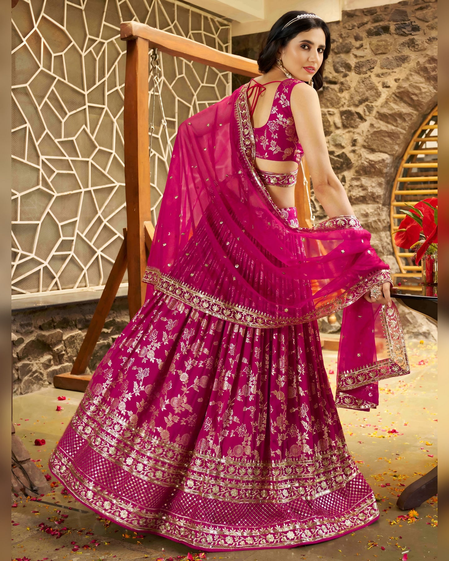 Woman in a pink traditional outfit with floral patterns in an indoor setting.