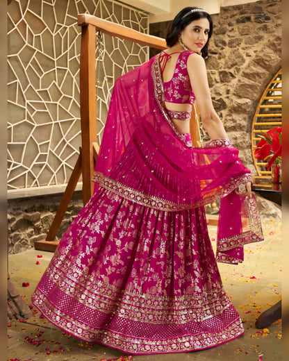 Woman in a pink traditional outfit with floral patterns in an indoor setting.