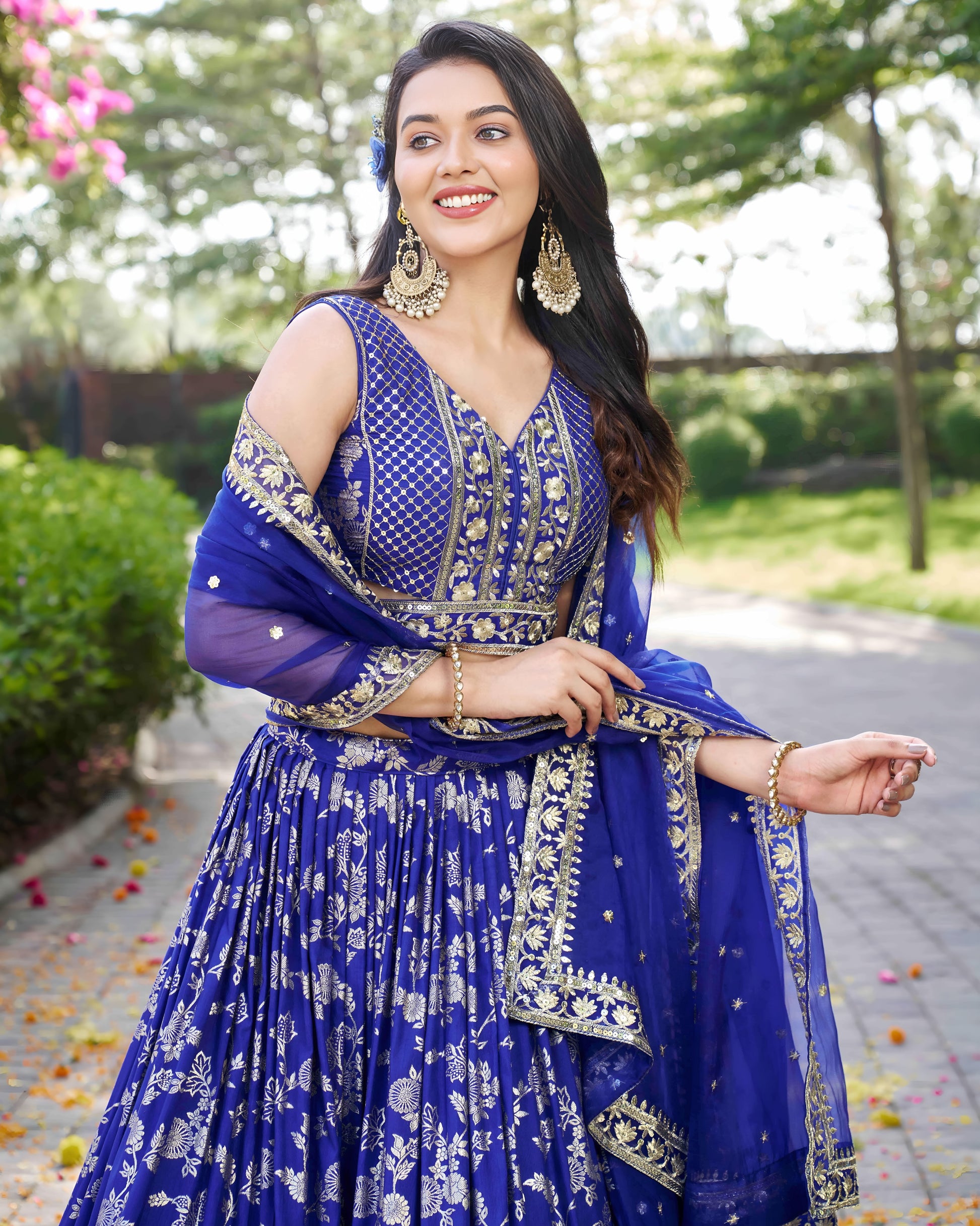 Woman in a blue traditional outfit with floral patterns outdoors.