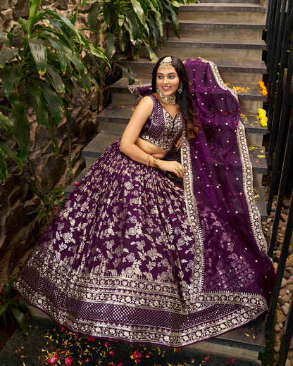 Woman in a purple embroidered traditional outfit sitting on steps with greenery around.