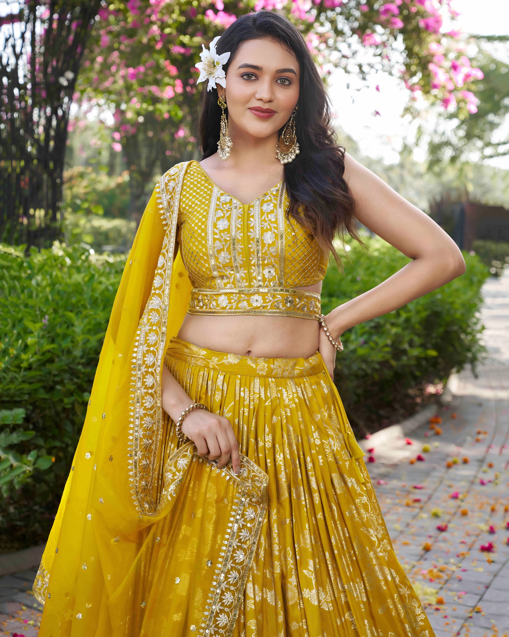 Woman in a yellow traditional outfit with floral decorations in an outdoor setting