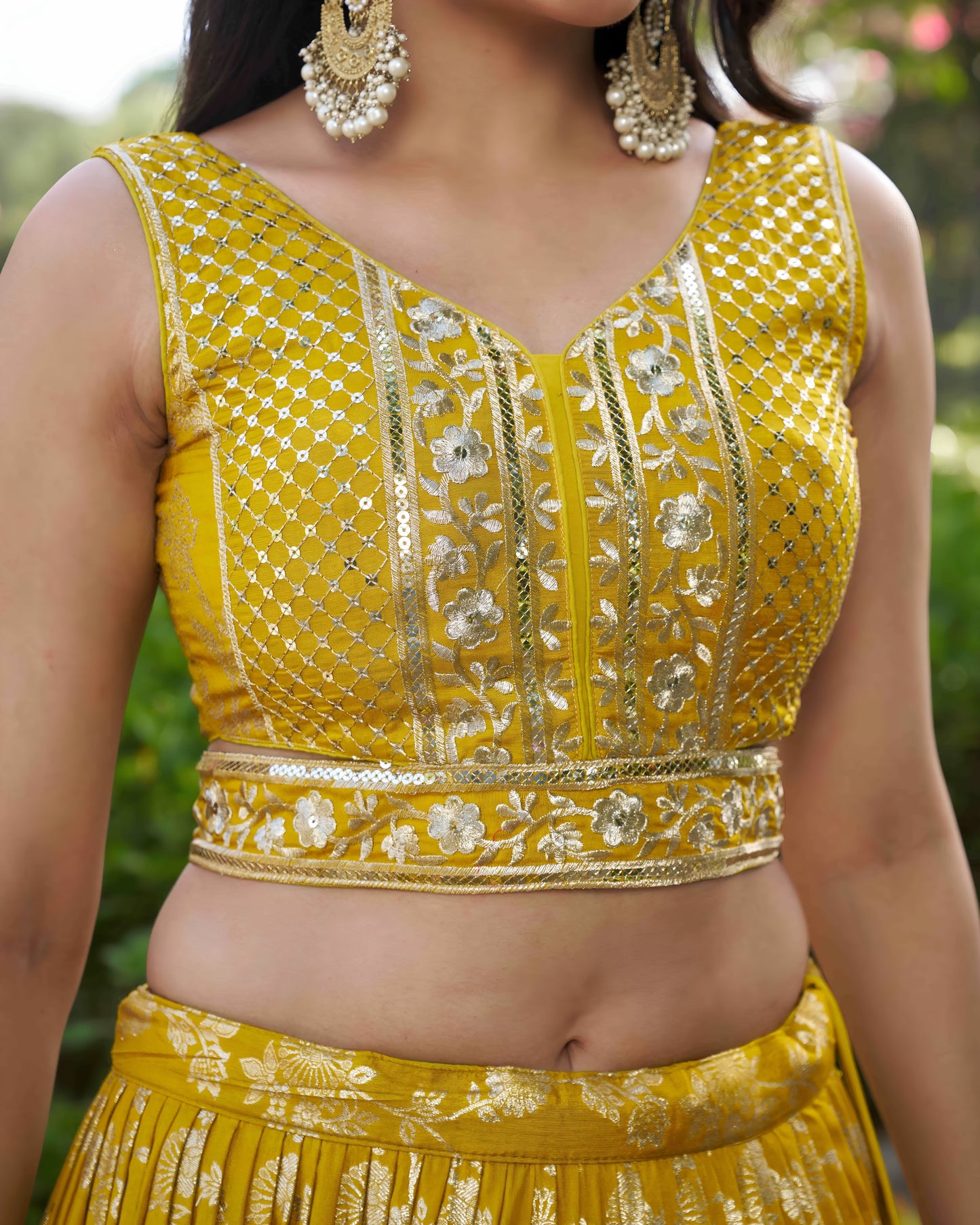 Yellow embroidered blouse with intricate patterns on a blurred green background