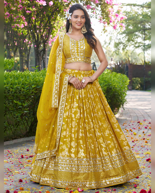Woman in a yellow traditional outfit with floral decorations in an outdoor setting.