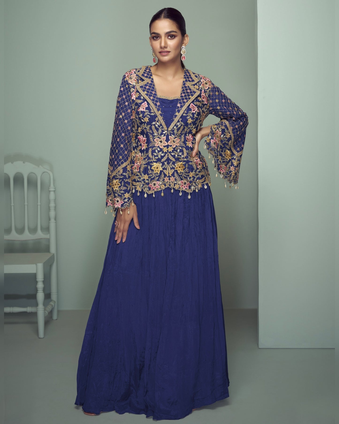 Woman wearing a blue outfit with floral embroidery in a minimalistic setting