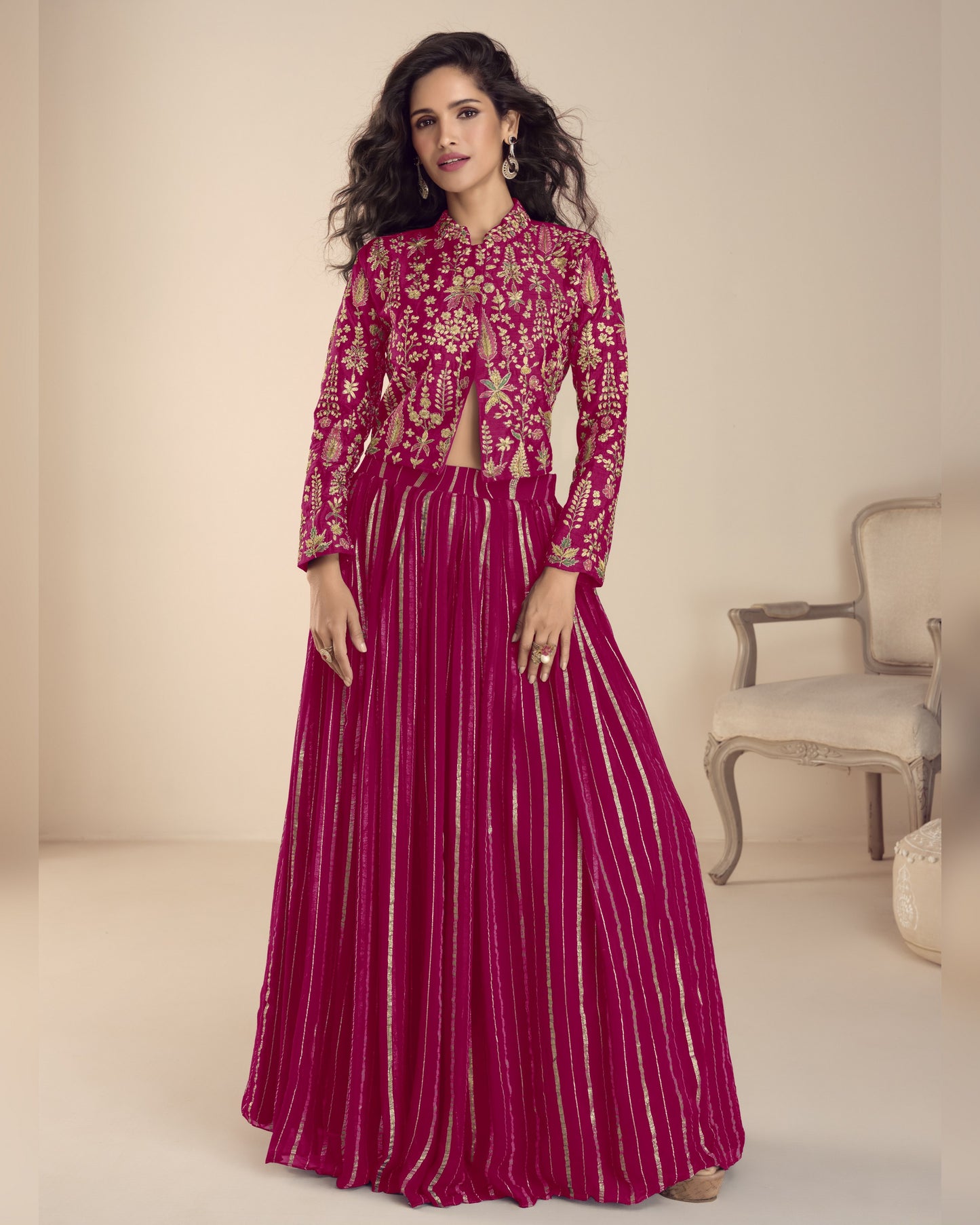 Woman wearing a pink traditional outfit with intricate designs in a well-lit room.