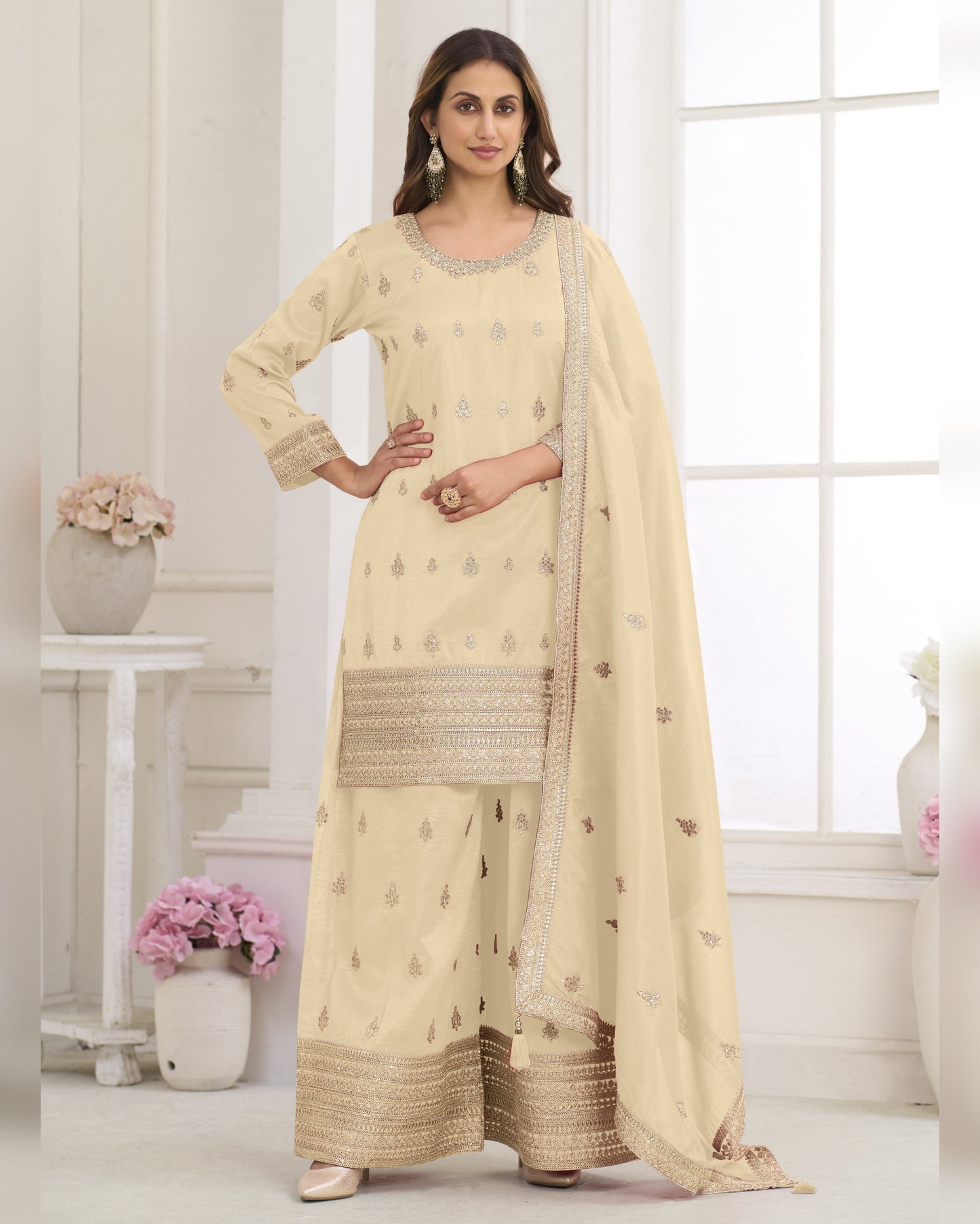 Woman wearing a beige traditional outfit with a matching dupatta in a bright room.