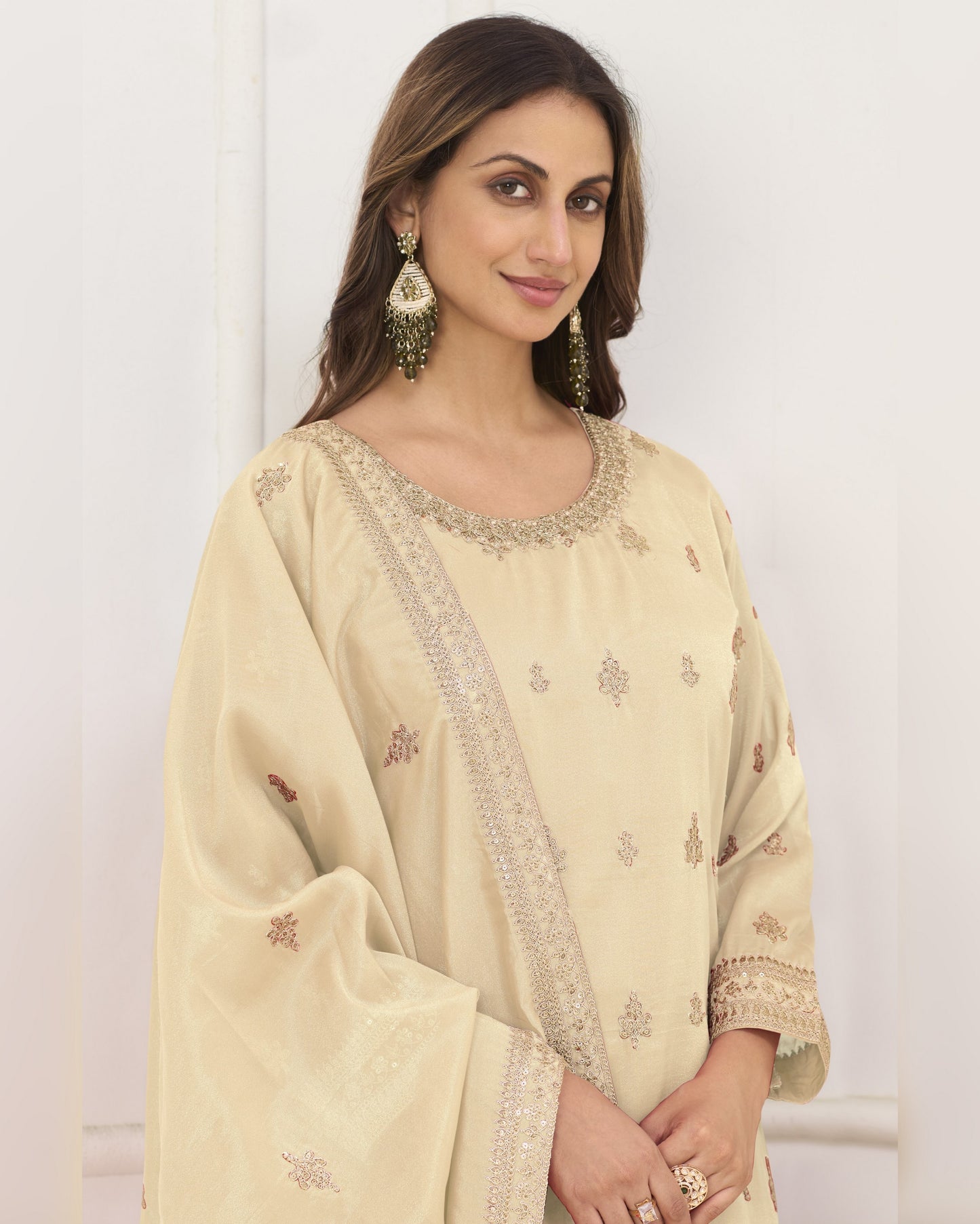 Woman wearing a beige embroidered traditional outfit with a white background
