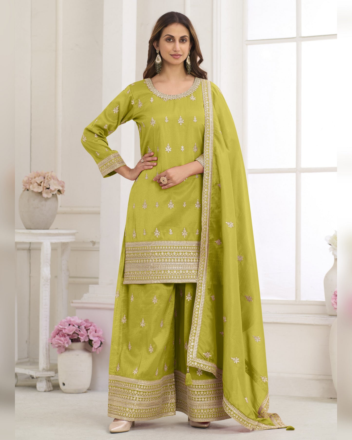 Woman wearing a green traditional outfit with a matching dupatta in a bright room.