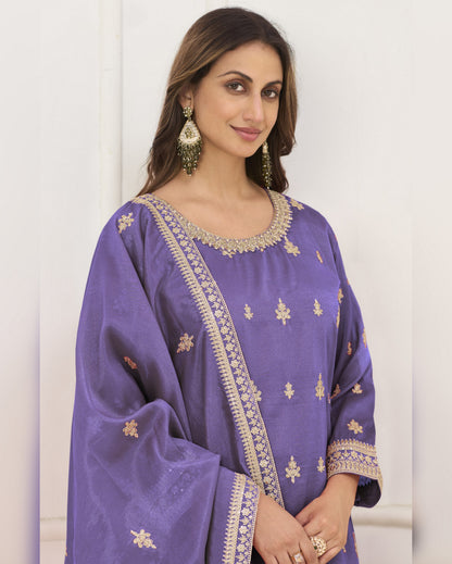Woman wearing a purple embroidered traditional outfit against a white background