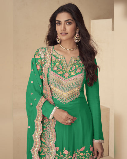 Woman wearing a green embroidered traditional outfit with a beige background