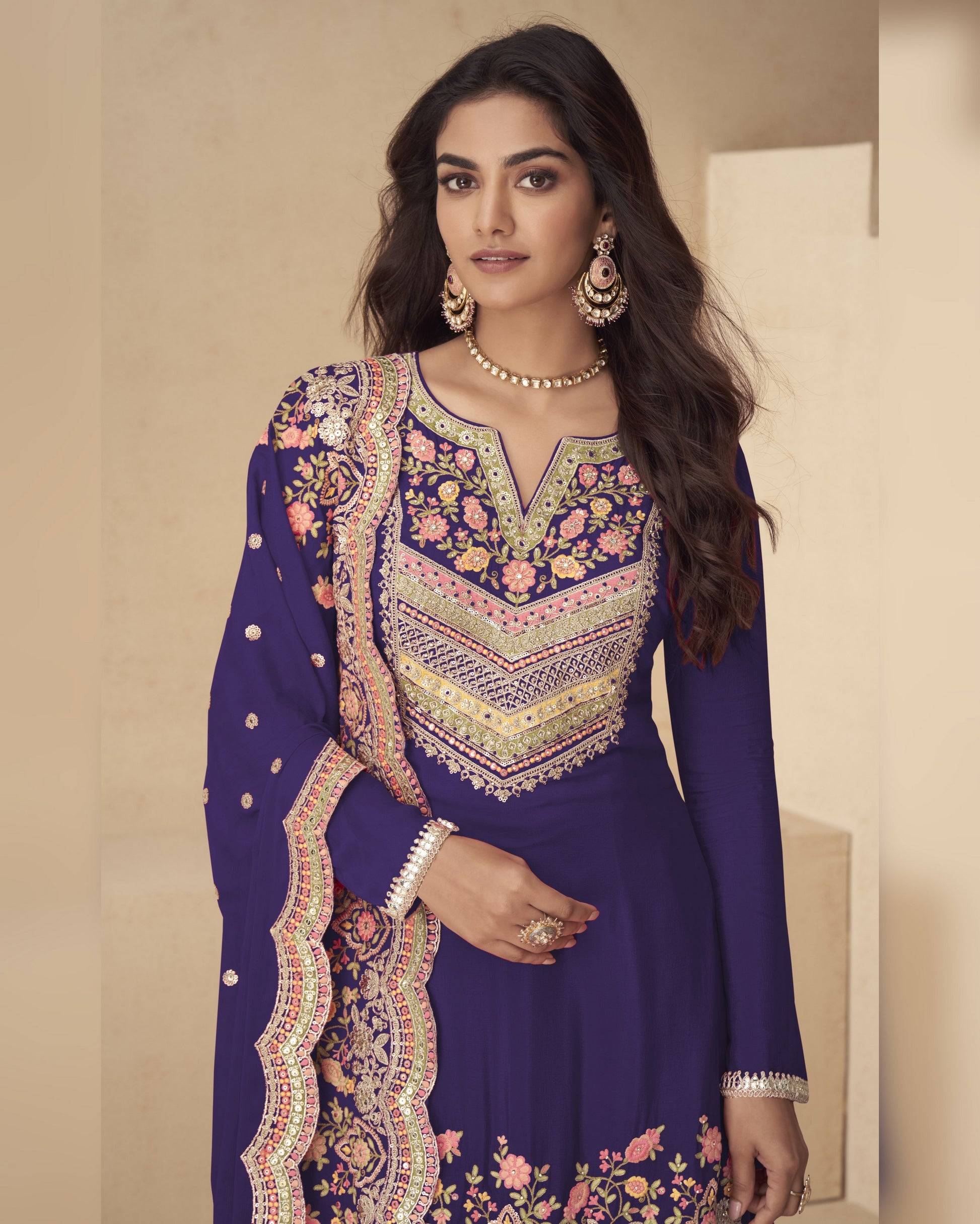 Woman wearing a purple embroidered traditional outfit with a neutral background