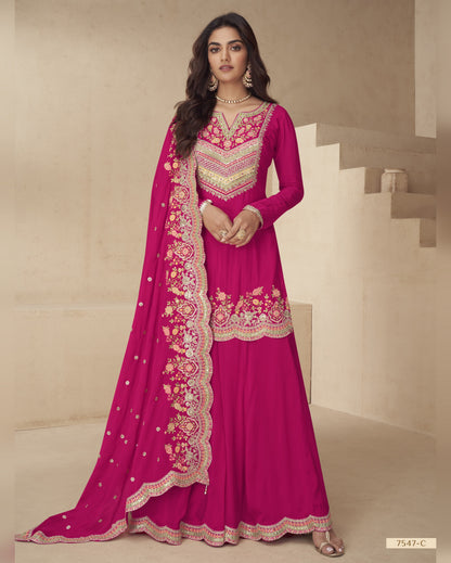 Woman wearing a pink embroidered traditional outfit with a matching dupatta on a neutral background