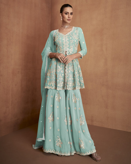 Woman wearing a light blue embroidered traditional outfit against a brown background