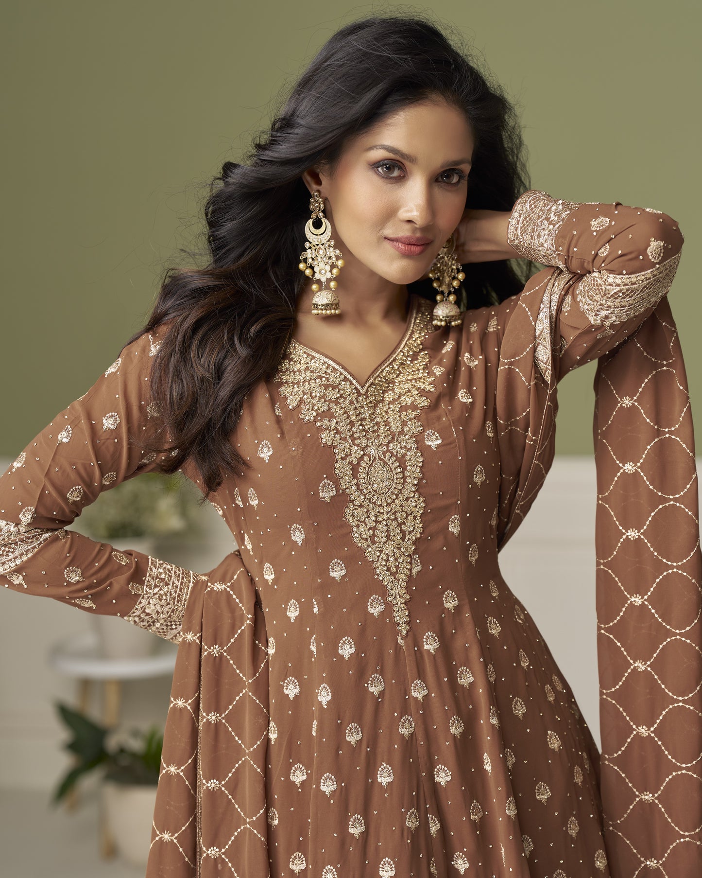 Woman wearing a brown and gold embroidered traditional outfit with a blurred background