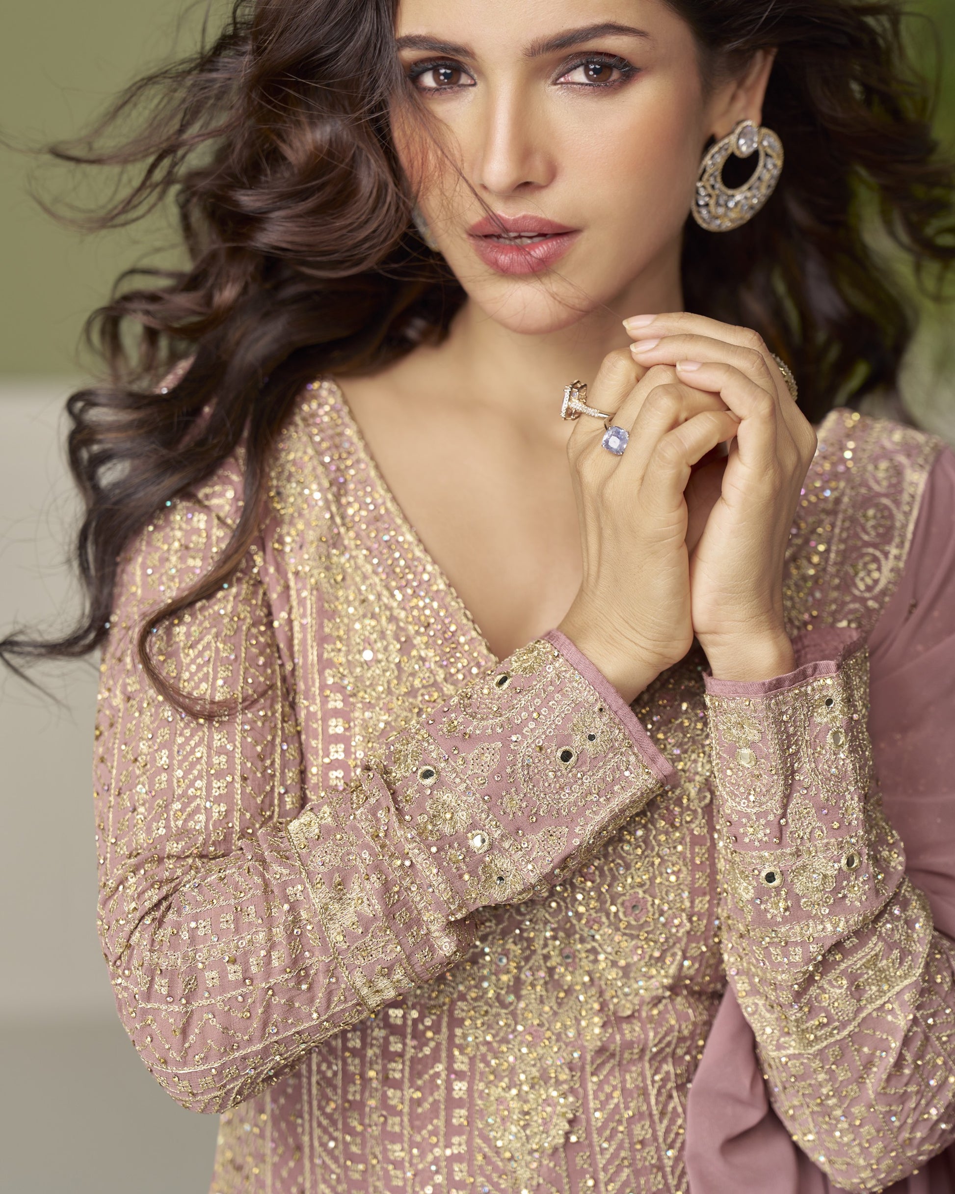 Woman wearing a sparkling gold and pink traditional outfit with jewelry.