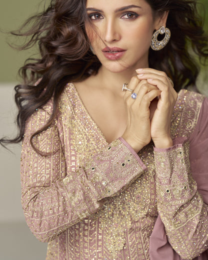 Woman wearing a sparkling gold and pink traditional outfit with jewelry.