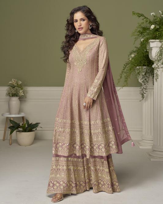 Woman wearing a traditional outfit with intricate patterns in a decorated room.