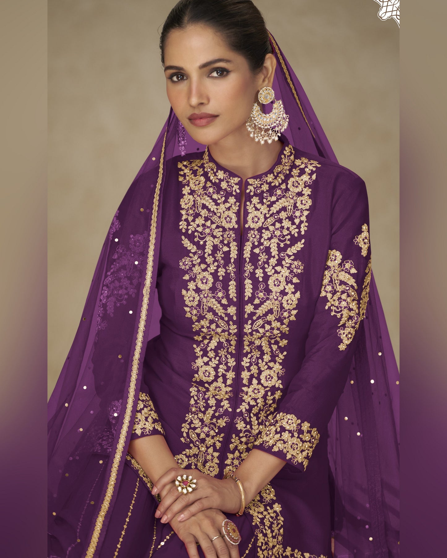 Woman wearing a purple embroidered outfit with gold details on a beige background