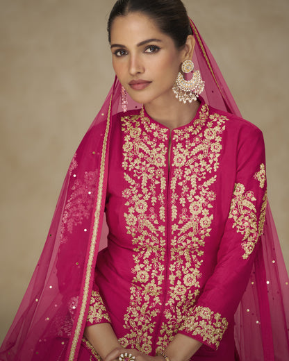 Woman wearing a pink embroidered outfit with a matching dupatta on a beige background