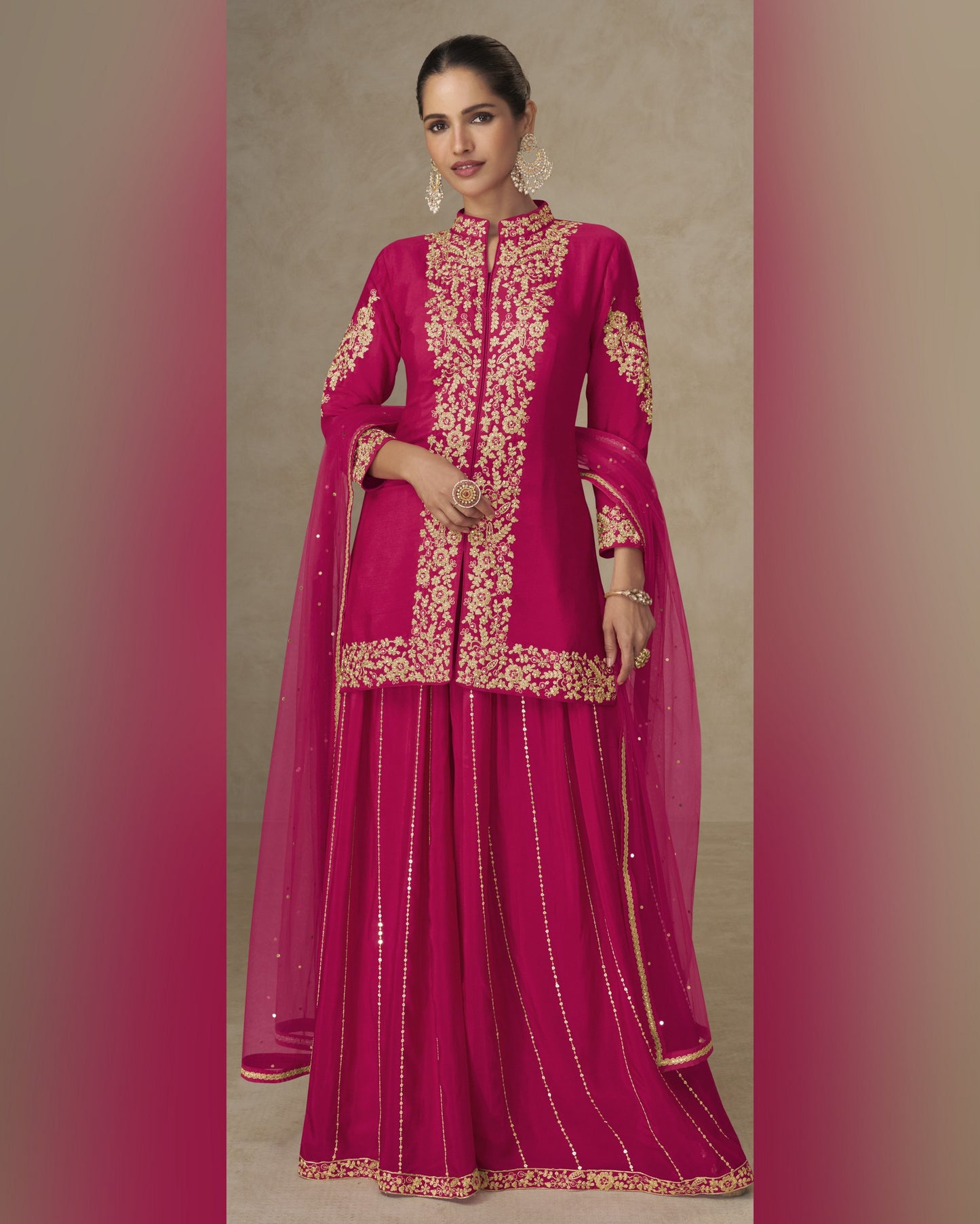 Woman wearing a pink traditional outfit with gold embroidery on a beige background