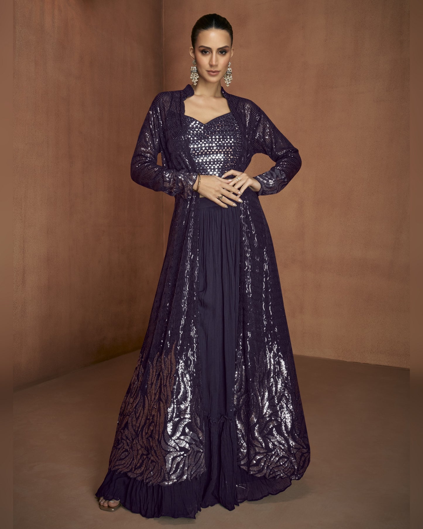 Woman wearing a long, dark purple dress with sequin detailing against a brown background