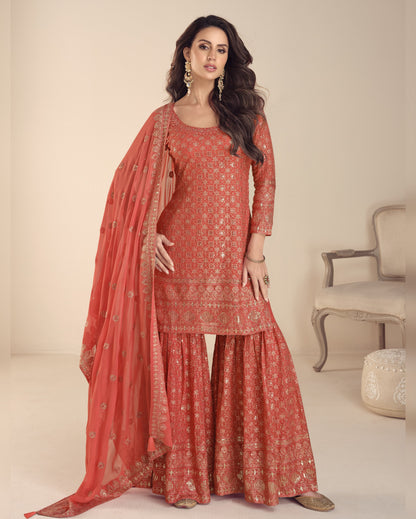 Woman wearing a red traditional outfit with a matching dupatta in a neutral setting