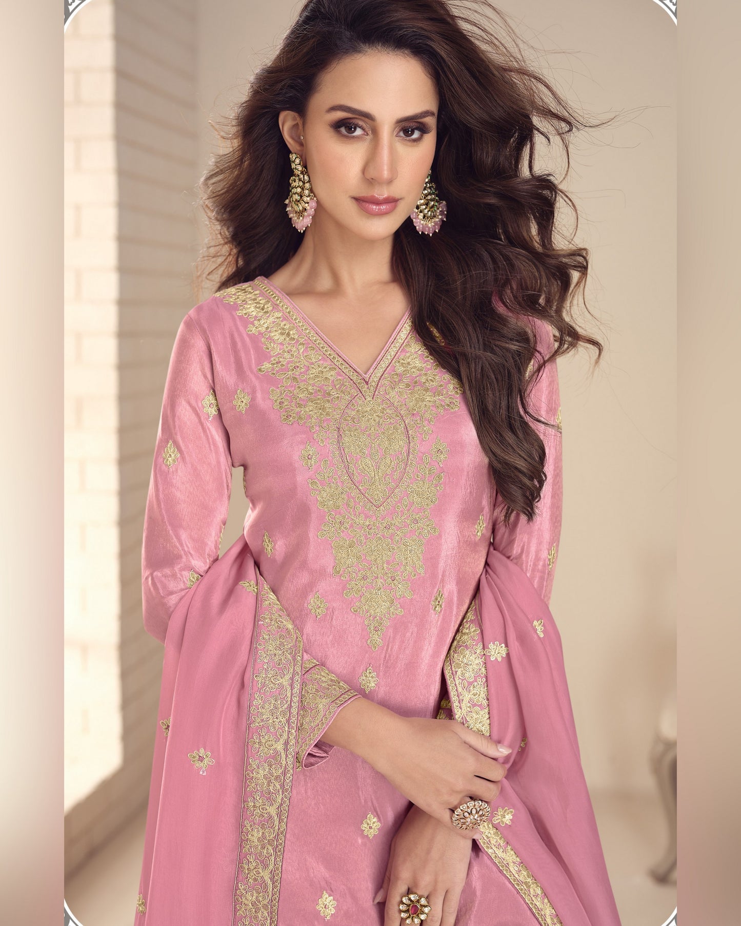 Woman wearing a pink embroidered saree with a neutral background