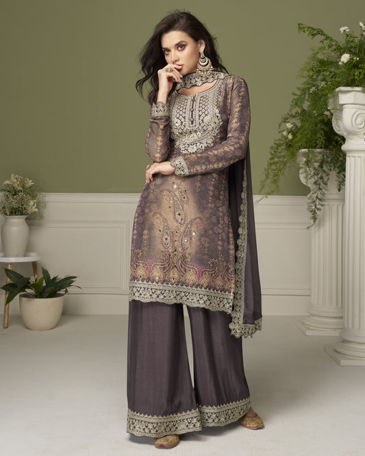 Woman wearing a traditional outfit with intricate patterns in a decorated room.