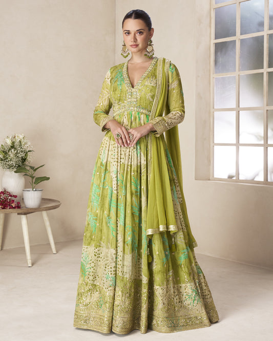 Woman wearing a green traditional outfit in a well-lit room with a window and small table.