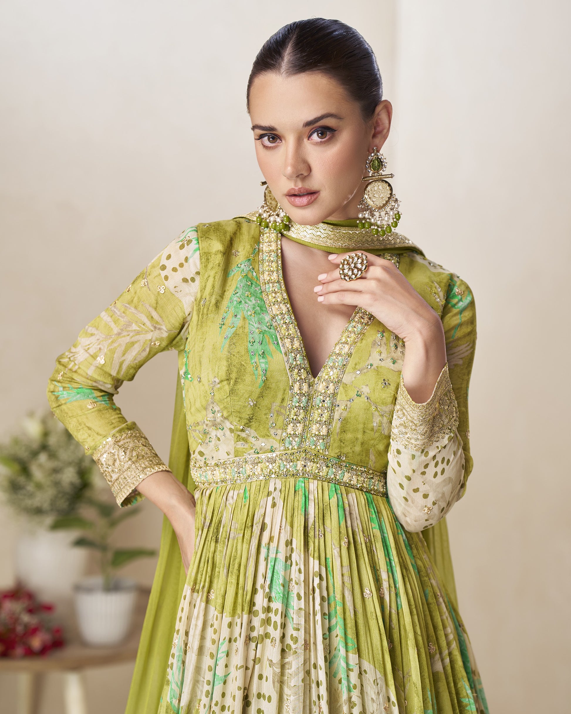 Woman wearing a green and white embroidered traditional outfit with a plain background