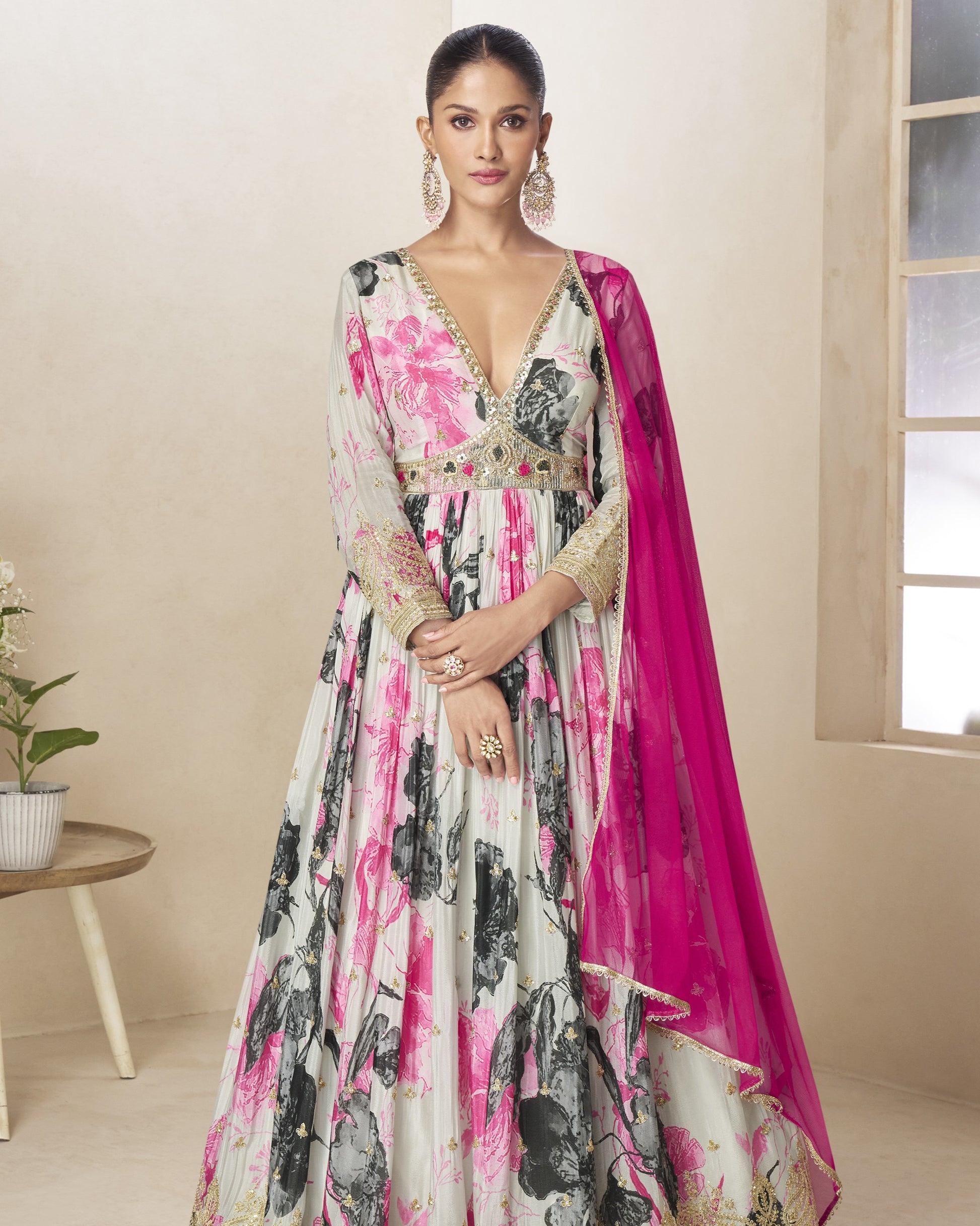 Woman wearing a floral dress with a pink dupatta indoors.