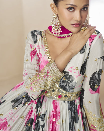 Woman wearing a traditional outfit with floral patterns and jewelry against a beige background