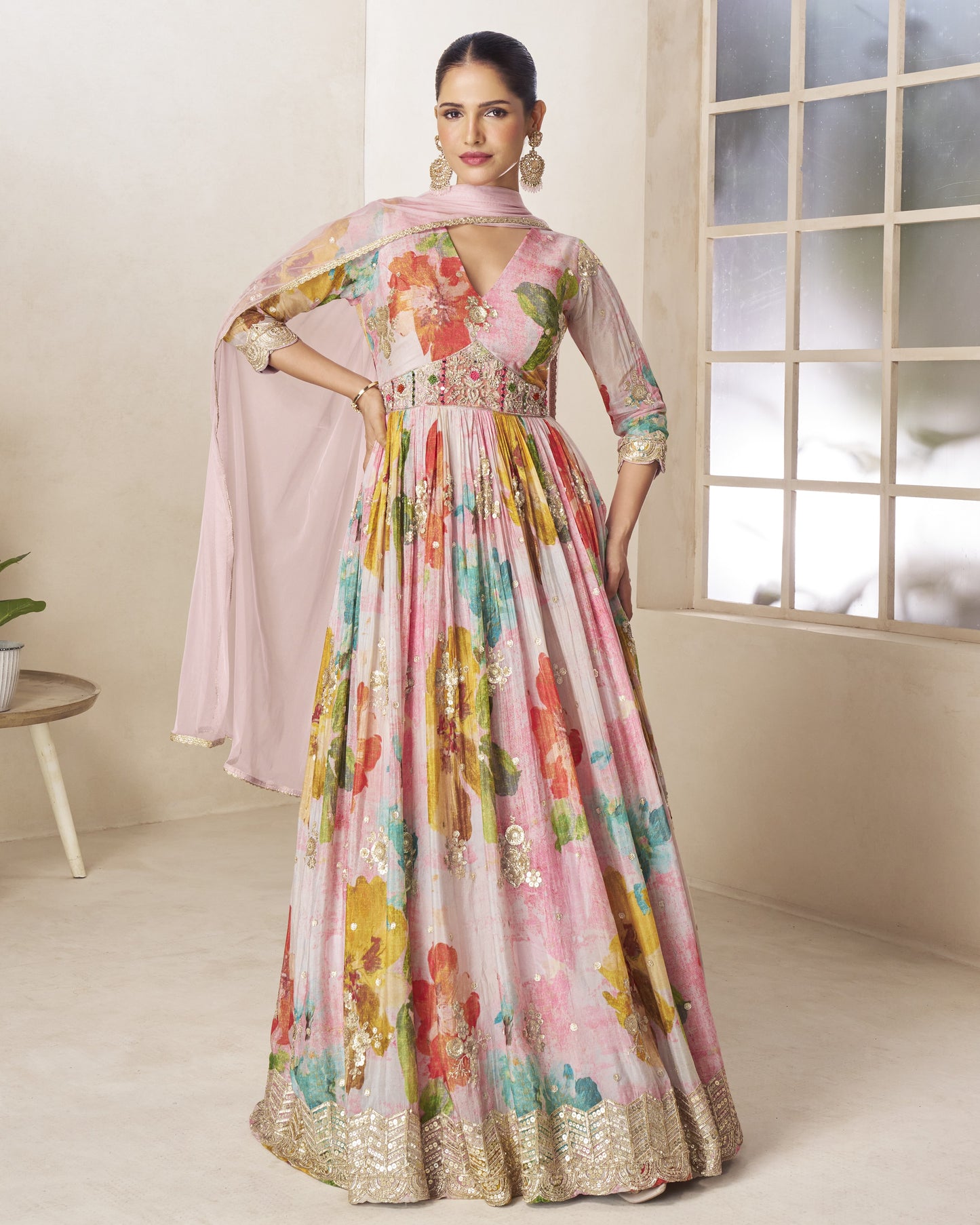 Woman wearing a colorful floral dress in a room with a window.