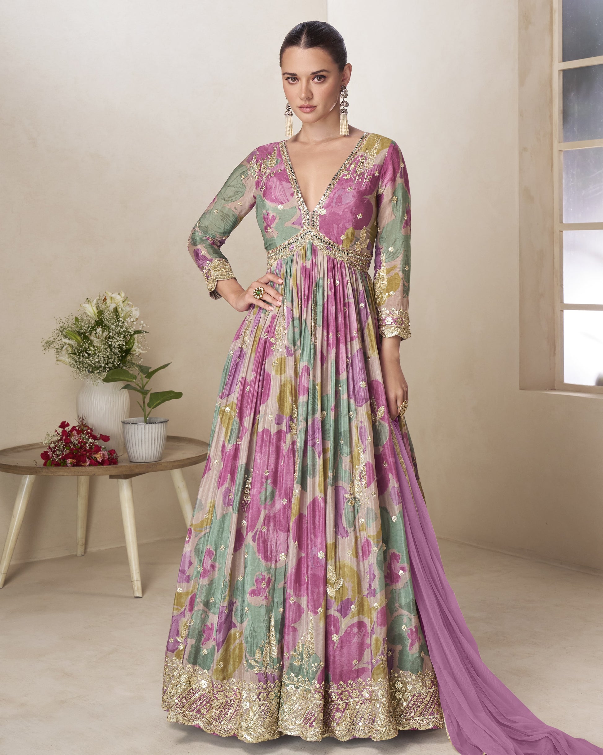 Woman wearing a floral dress with a matching dupatta in a room setting.
