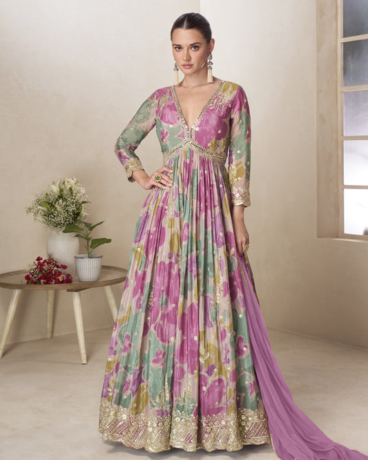 Woman wearing a floral dress with a matching dupatta in a room setting.