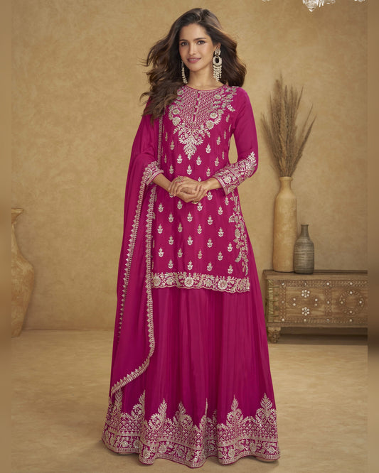 Woman wearing a pink embroidered traditional outfit with a beige background