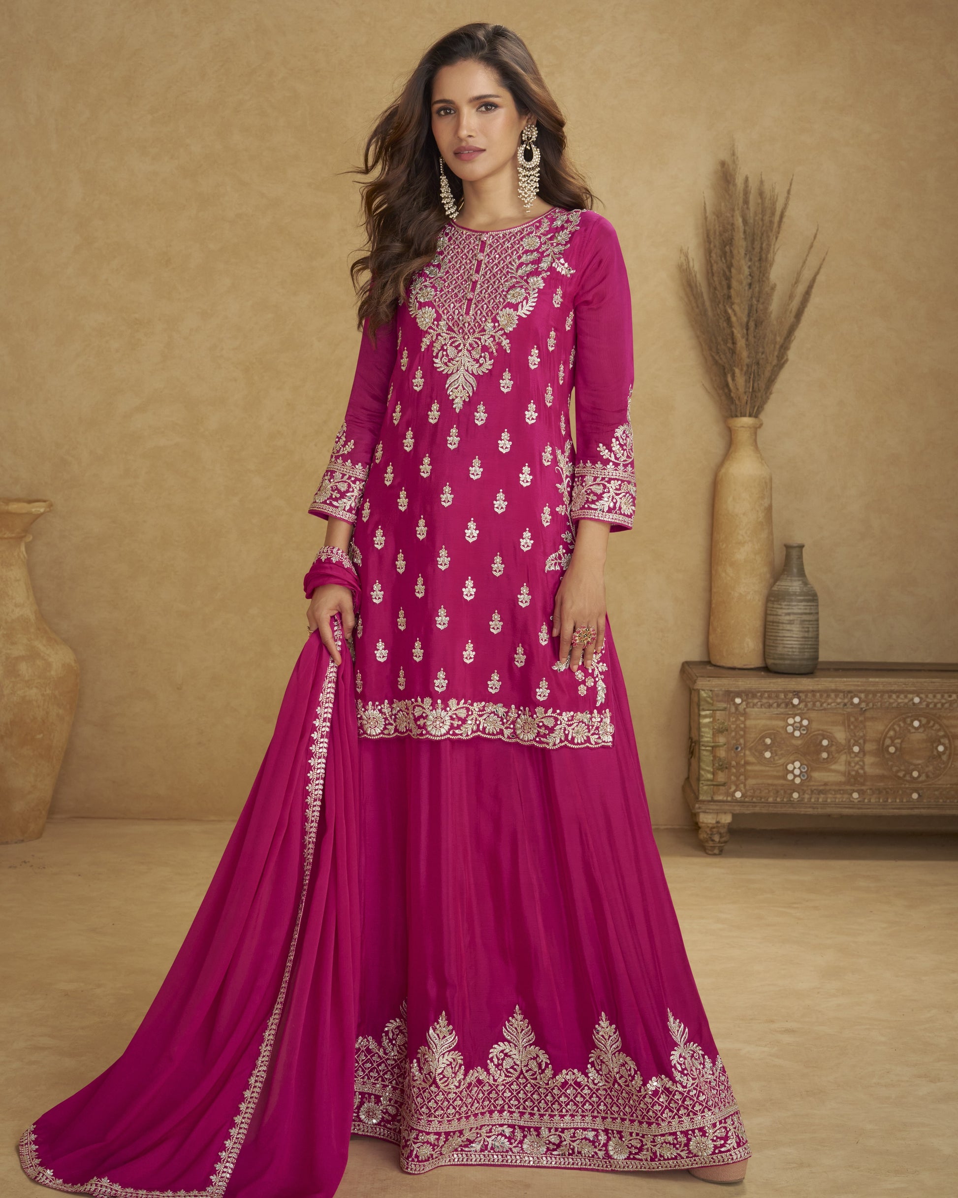 Woman wearing a pink embroidered traditional outfit with a beige background