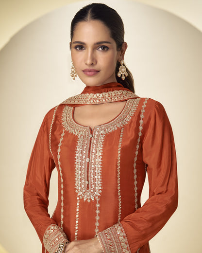 Woman wearing an orange embroidered traditional outfit on a beige background