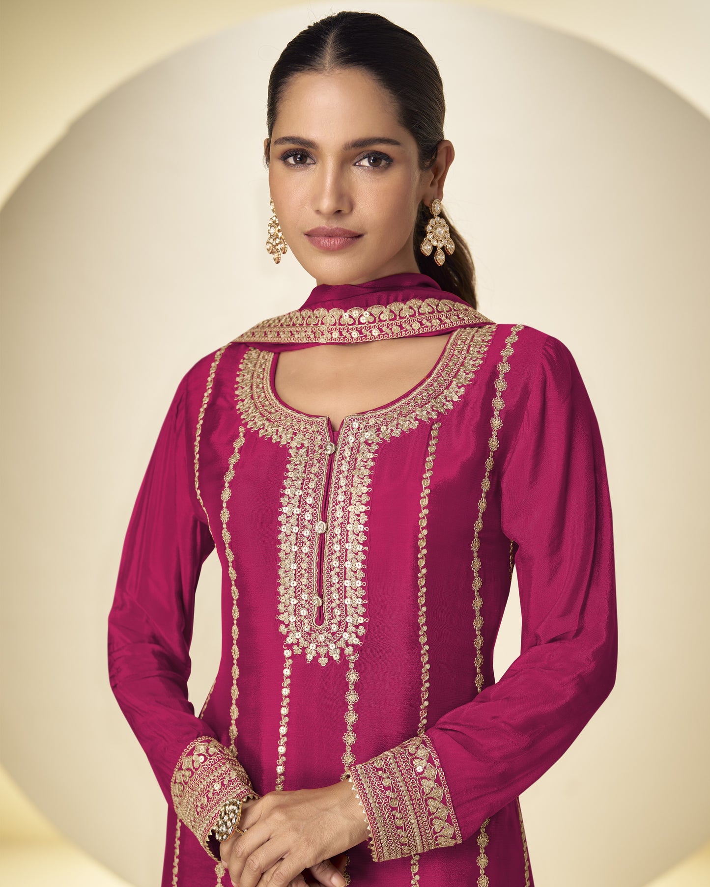 Woman wearing a pink embroidered traditional outfit against a neutral background